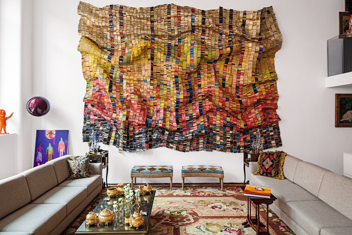 A hotel room with a large woven textile wall hanging by Basma Alsuliman, layered with color and texture