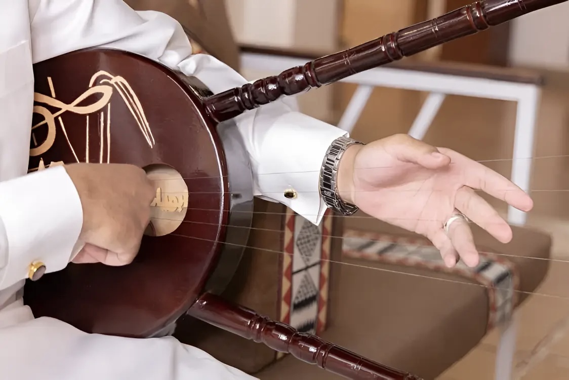 A musician playing a traditional Simsimiyya lyre at sunset in Alula