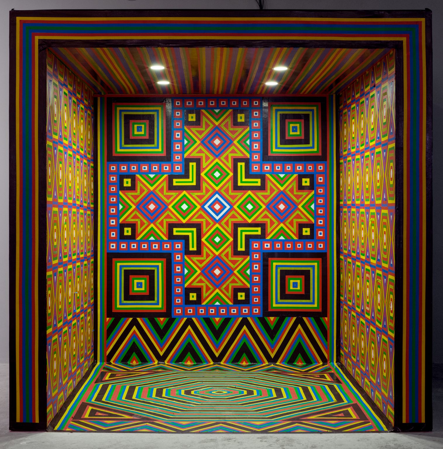 A hotel room wrapped in vibrant Al-Qatt Al-Asiri geometric patterns by Dana Awartani
